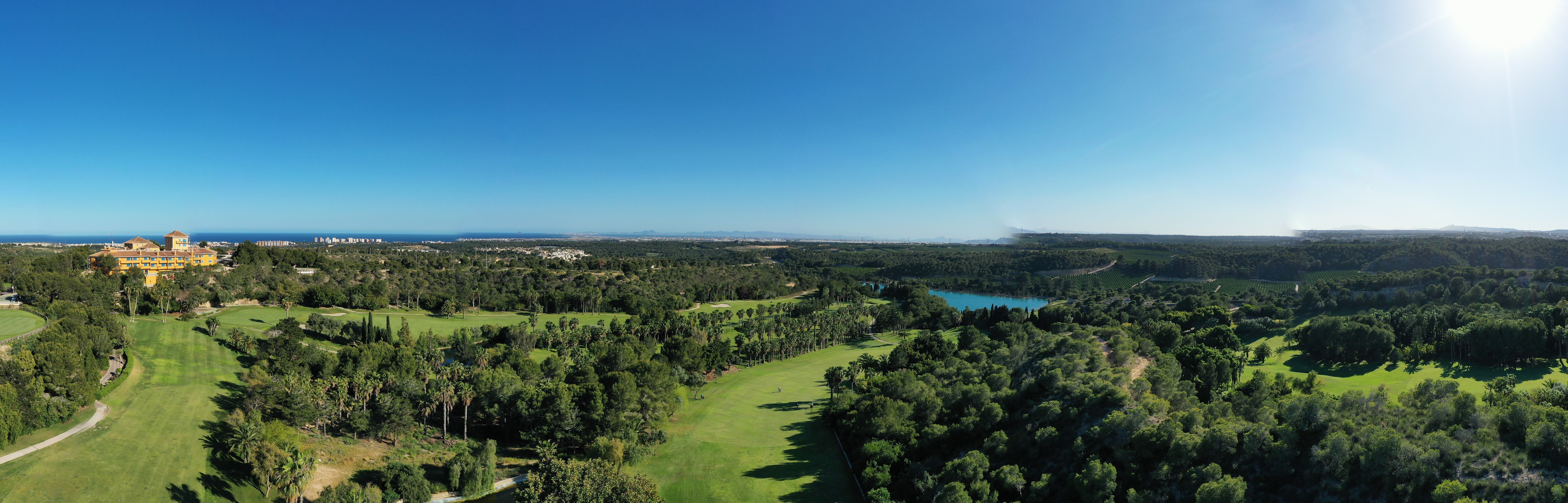 Golfbane som bader i sol og blå himmel