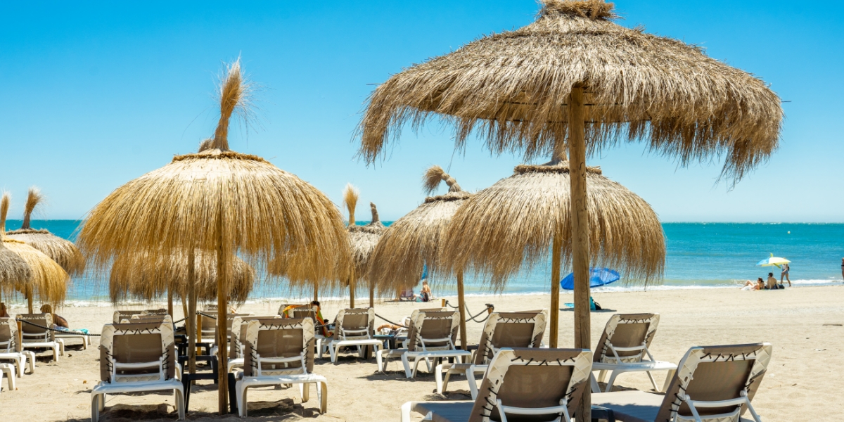 Solsenger under parasoller på stranden