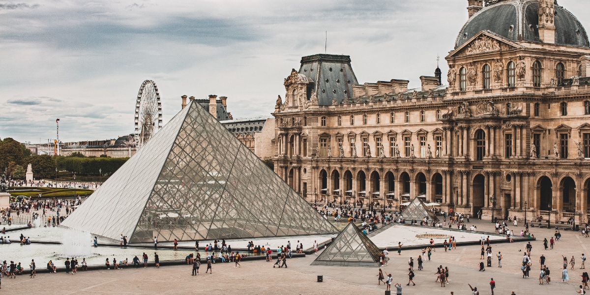 Louvre i Paris med glasspyramiden i front og litt av museet bak