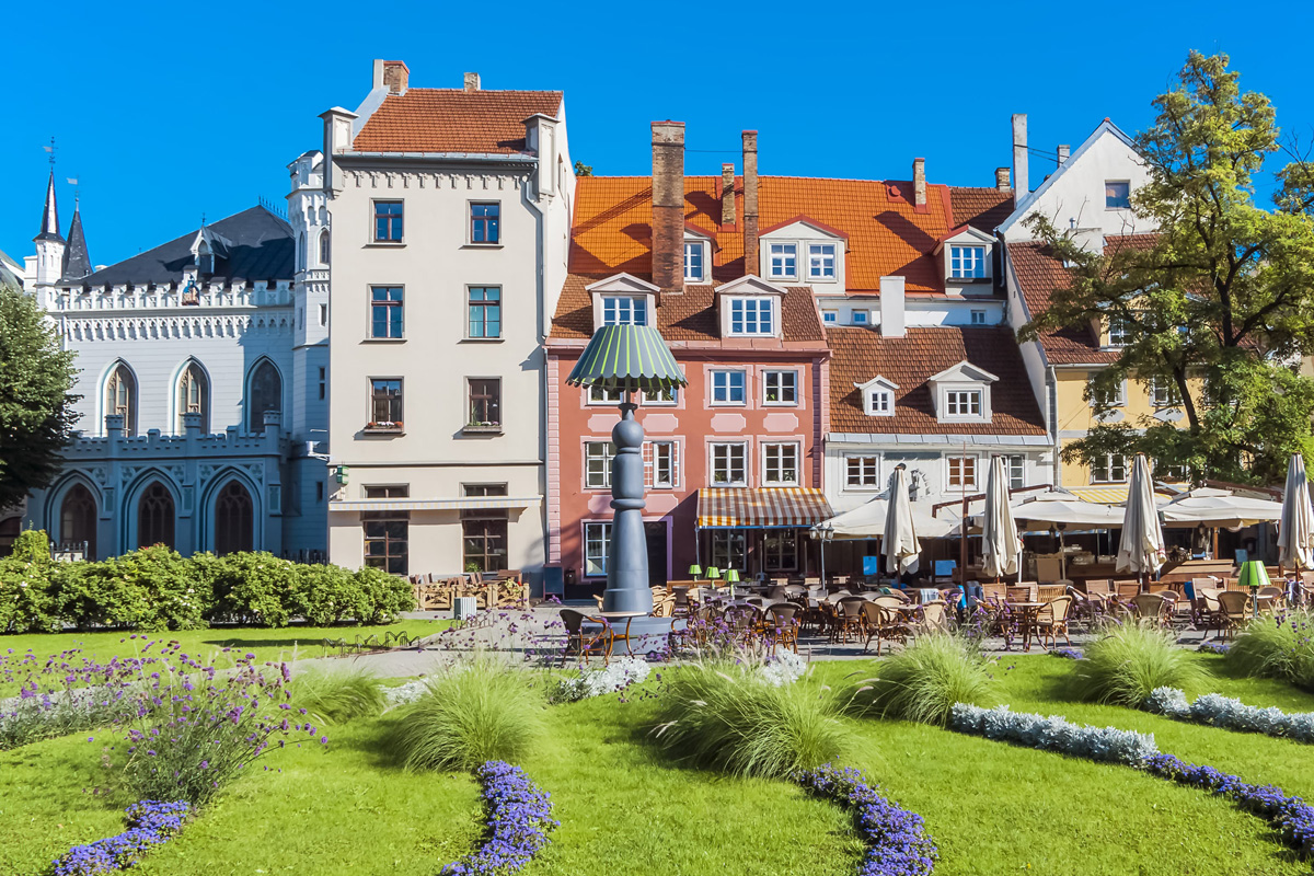 Grønn plen med lilla blomster foran gamle bygninger