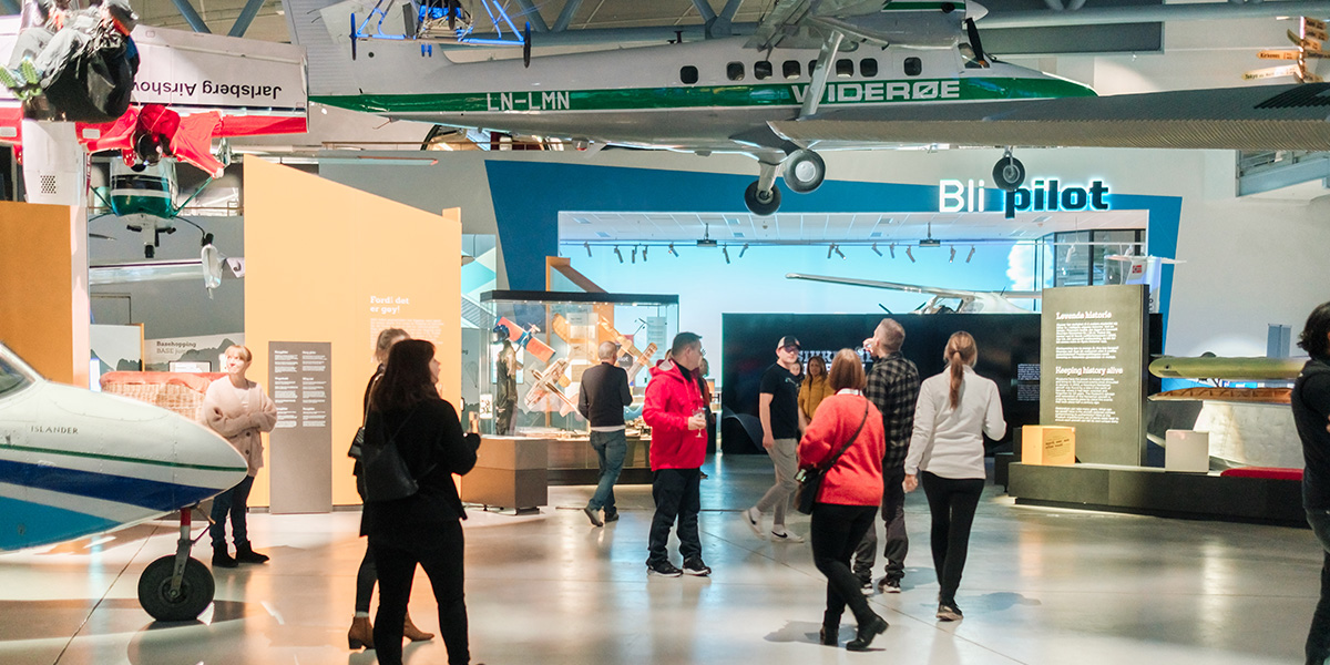 Flymuseum med diverse småfly og mennesker som går rundt