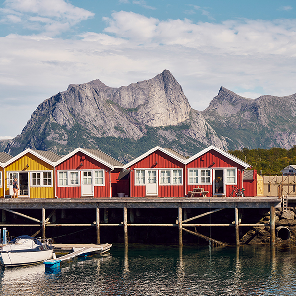 Rorbuer med fjell i bakgrunnen og sjø foran