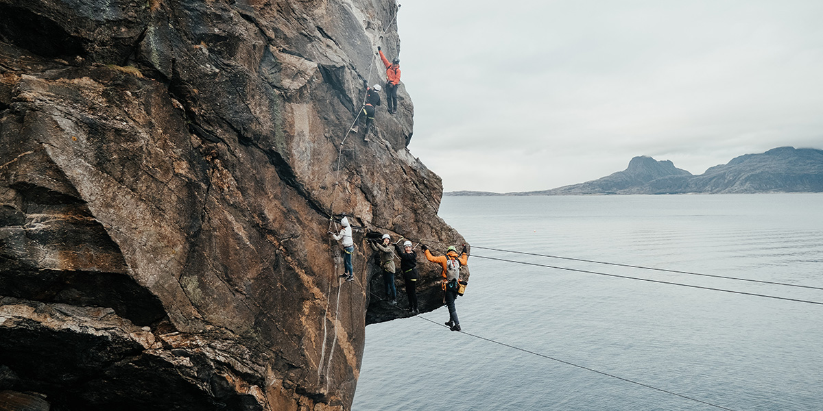 Fjellklatrere i en fjellside med havet under seg