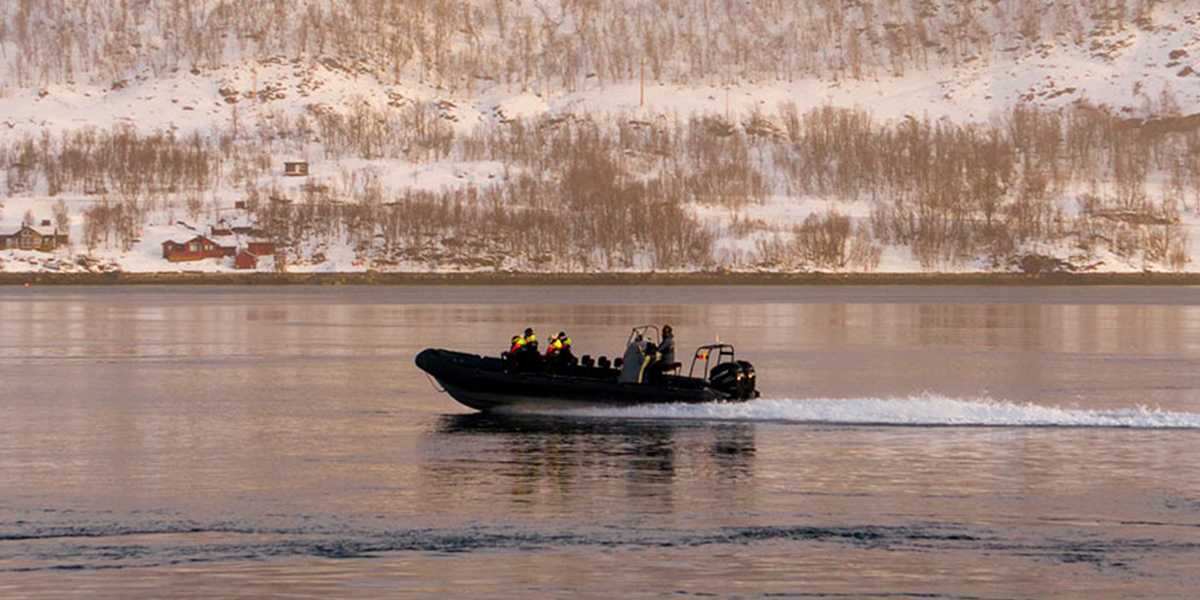 En RIB-båt på sjøen med et vinterlandskap i bakgrunnen