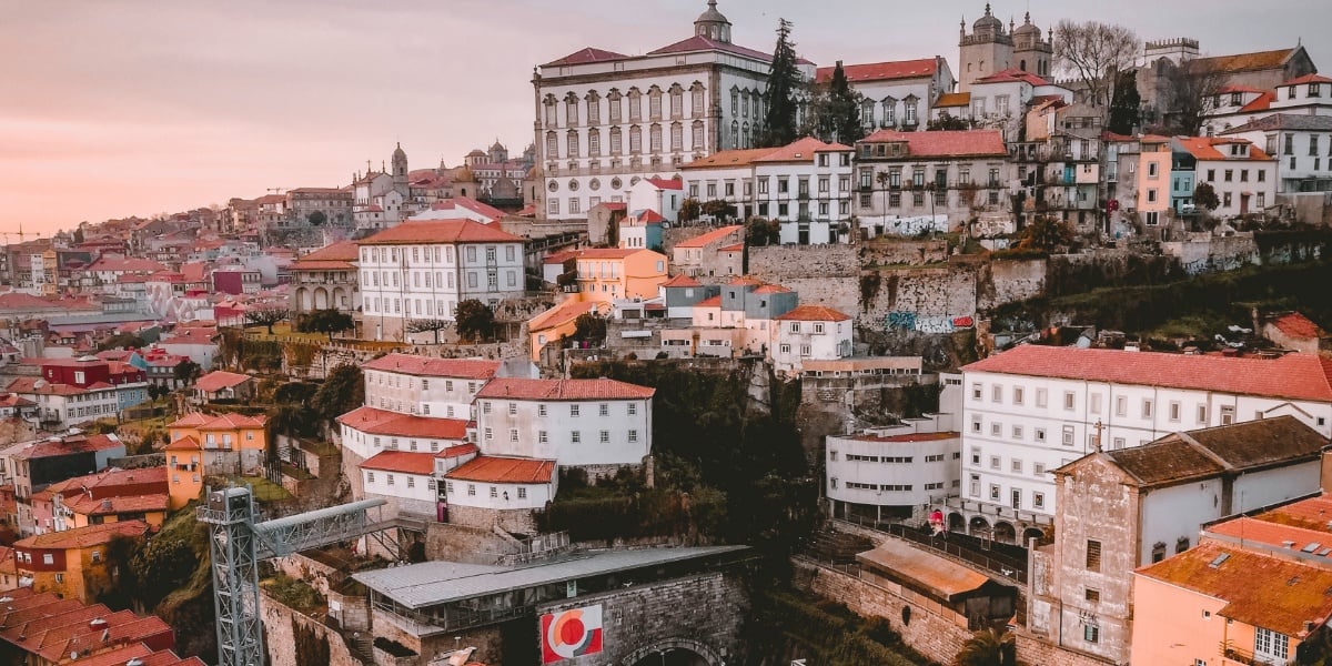 Oversiktsbilde over Porto i solnedgang. Røde teglsteinstak og hvite bygninger.