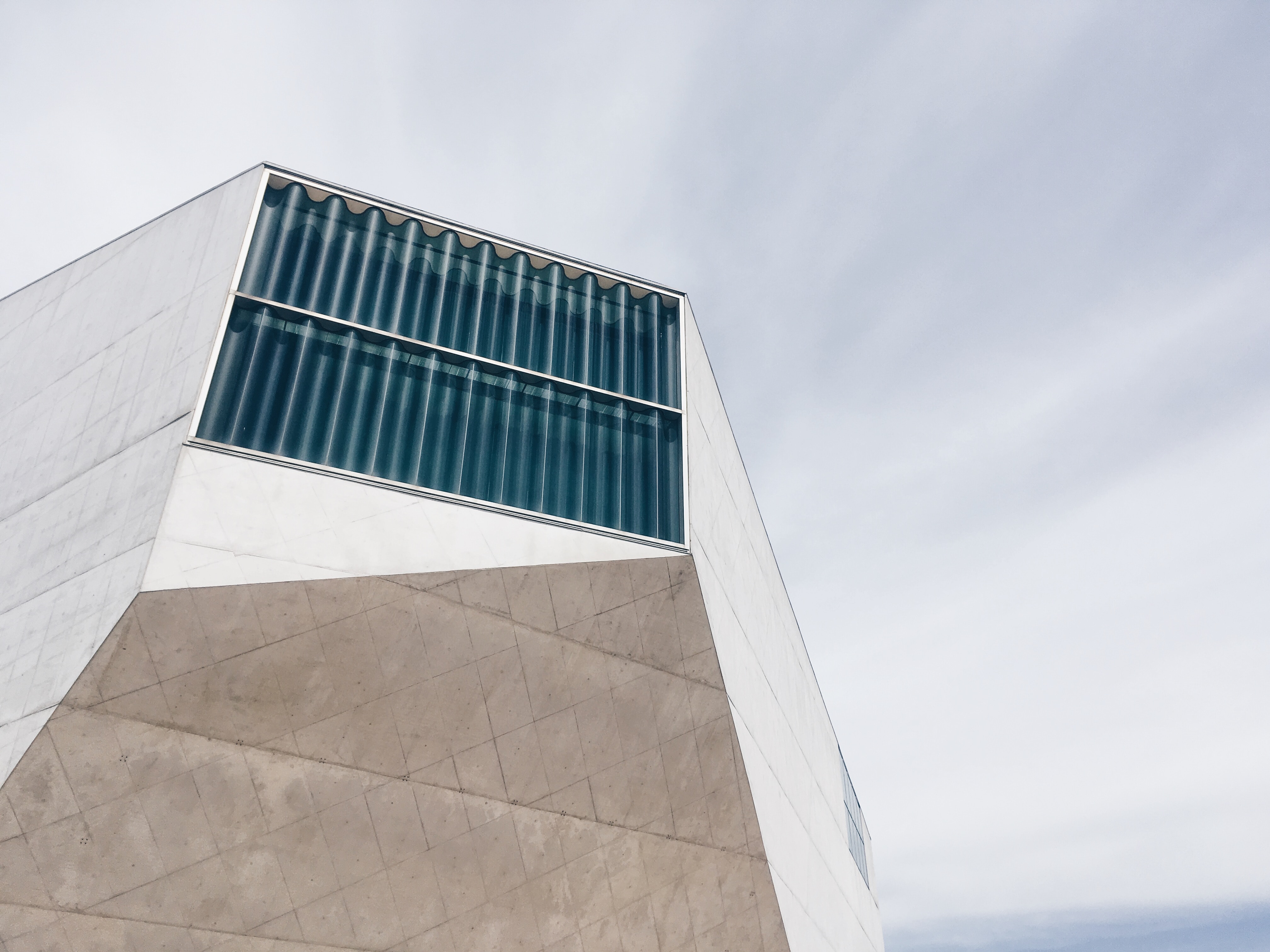 Modernistisk bygning i hvit marmor med vindu i bølgete glass.