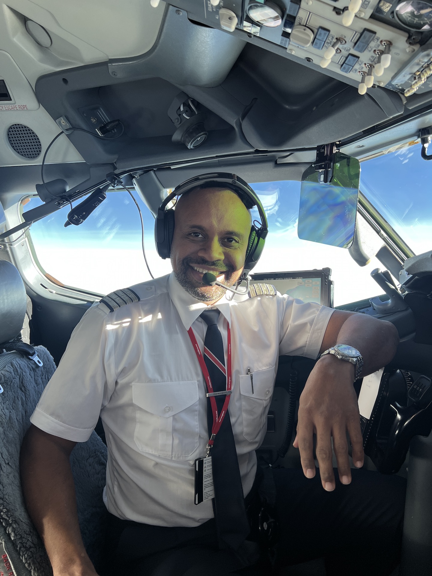 Man in captainuniform smiles from cockpit
